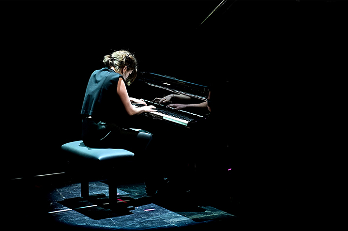 Foto von Lilli Eisenberg am Klavier mit einem Lichtspot