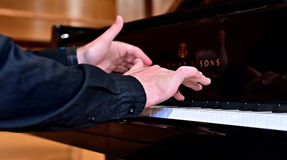 Zwei Hände spielen auf einer Klaviertastatur