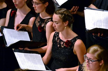 Foto von Sängerinnen des Madrigalchors mit Noten auf einer Bühne