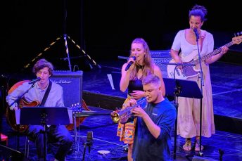 Foto von Musikerinnen und Musikern der Salsaband mit verschiedenen Instrumenten auf der Bühne