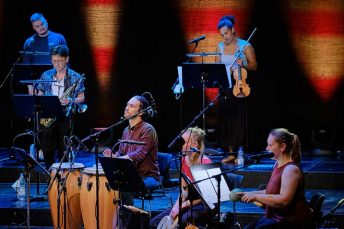 Foto von Musikerinnen und Musikern der Salsaband mit verschiedenen Schlaginstrumenten auf einer Bühne