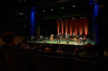Foto von Musikerinnen und Musikern der Salsaband auf einer Bühne aufgenommen von hinter dem Publikum