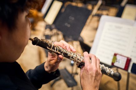 Person spielt Oboe und hält das Instrument mit beiden Händen