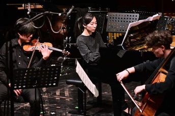 Foto von einem Cellisten, einem Geiger und einer Pianistin des ensemble oktopus auf einer Bühne