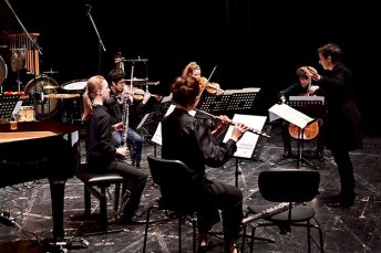 Foto von Musikerinnen und Musikern des ensemble oktopus auf einer Bühne mit der Dirigentin Konstantia Gourzi