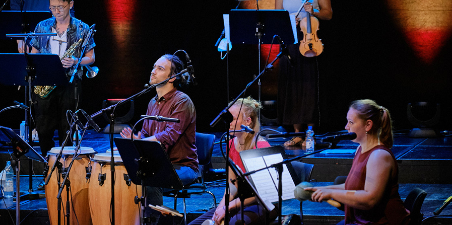Foto von Musikerinnen und Musikern der Salsaband mit Schlaginstrumenten auf der Bühne